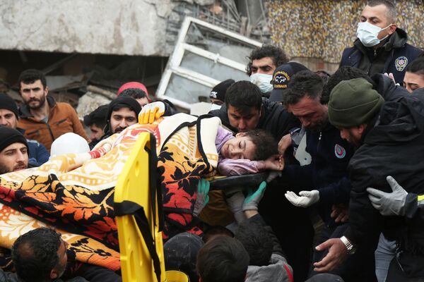 Люди несут девочку, пострадавшую в результате землетрясения в турецком городе Диярбакыр - Sputnik Молдова