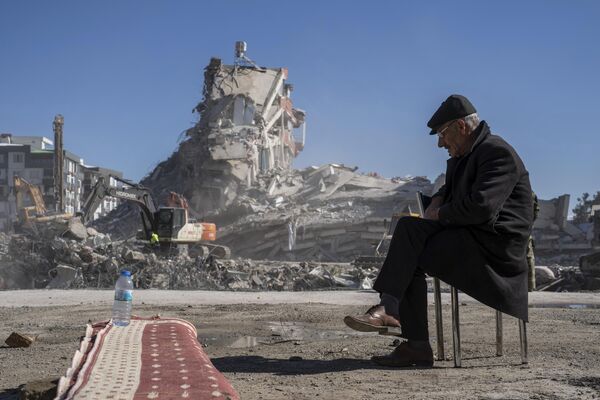 Mehmet Nasir Duran, în vârstă de 67 de ani, stă pe un scaun, în timp ce mașinile grele scot resturile dintr-o clădire, unde cinci dintre membrii familiei sale sunt prinși în Nurdagi, sud-estul Turciei, 9 februarie 2023 - Sputnik Moldova-România