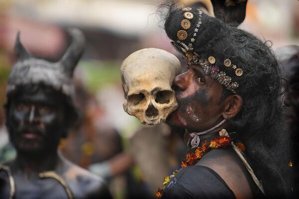 Поклонник бога Шивы держит зубами человеческий череп во время религиозного шествия по случаю фестиваля Маха Шиваратри в Праяградже, Индия. - Sputnik Молдова
