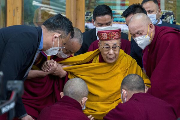 Тибетскому духовному лидеру Далай-ламе помогают монахи после того, как он обратился к группе студентов в храме Цуглакханг в Дхарамсале, Индия. - Sputnik Молдова