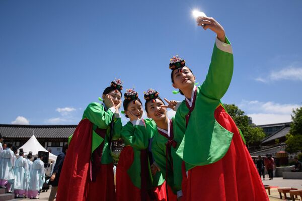 Молодые женщины в традиционных платьях ханбок после традиционной церемонии по случаю Дня совершеннолетия в деревне Намсан Ханок в Сеуле. - Sputnik Молдова