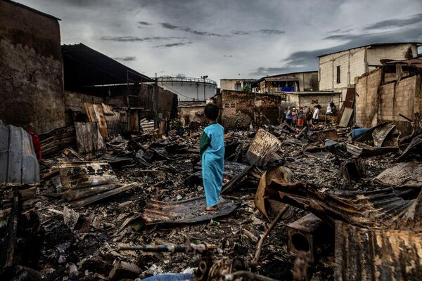 Мальчик стоит на руинах сгоревшего дома в жилом районе Плумпанга, север Джакарты, 4 марта 2023 года, после пожара на государственном складе топлива, которым управляет энергетическая компания Pertamina (фото АДИТЬИ АДЖИ / AFP). - Sputnik Молдова