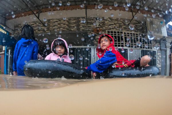 Дети используют надутые автомобильные камеры перед своим домом перед эвакуацией из зоны затопления в Йонг Пэн, штат Джохор, Малайзия, 4 марта 2023 года. - Sputnik Молдова
