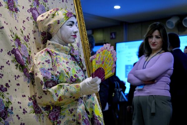 Посетительница смотрит на женщину, являющуюся частью интерактивной художественной инсталляции, во время Арабского форума по устойчивому развитию в Бейруте, Ливан. - Sputnik Молдова