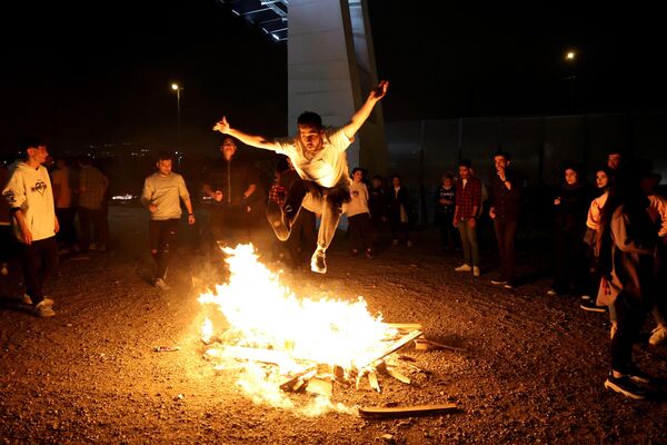 Иранец прыгает через костер во время праздника огня, или Чахаршанбе Сури, который проводится ежегодно в последнюю среду накануне весеннего праздника Навруз в Тегеране. - Sputnik Молдова