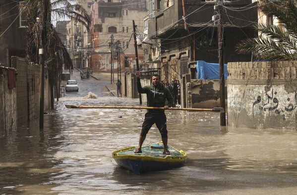 Палестинец плывет на лодке по затопленной после сильного дождя улице в лагере беженцев Аль-Шати в секторе Газа. - Sputnik Молдова