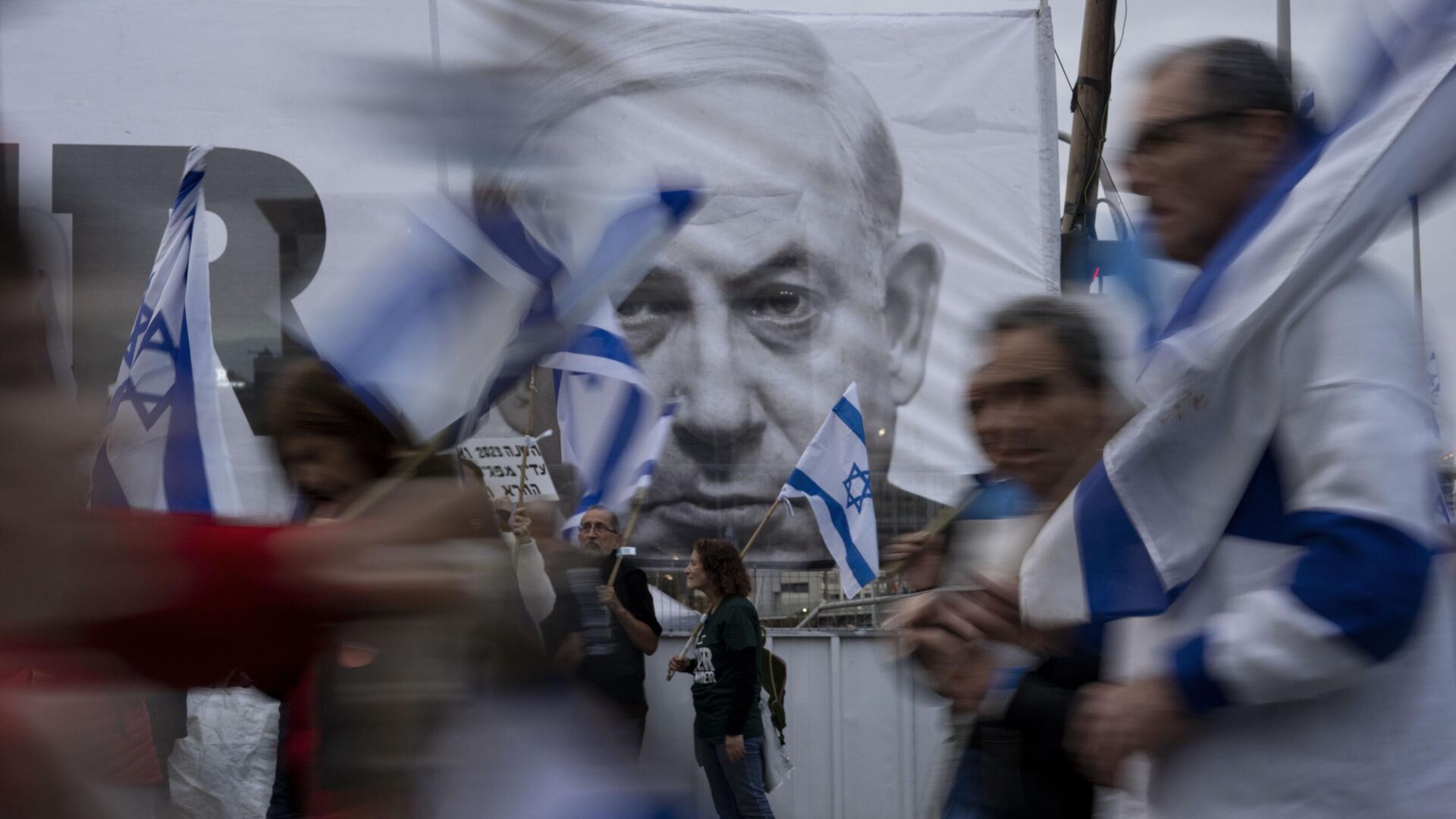 Демонстранты с  флагами Израиля рядом с баннером с изображением премьер-министра Биньямина Нетаньяху во время акции  против реформы судебной системы в Тель-Авиве, Израиль - Sputnik Moldova, 1920, 15.11.2023