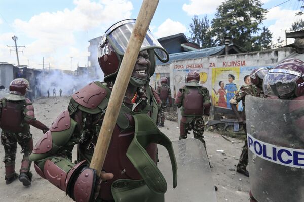 Сотрудник полиции по борьбе с беспорядками жмурится от слезоточивого газа на массовом митинге в трущобах Матаре в Найроби, Кения. - Sputnik Молдова