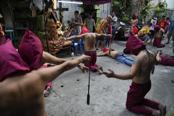 Филиппинцы в капюшонах молятся в рамках ритуалов Великого четверга, чтобы искупить грехи или исполнить клятвы за ответ на молитву 6 апреля 2023 года в городе Мандалуйонг, Филиппины.  - Sputnik Молдова