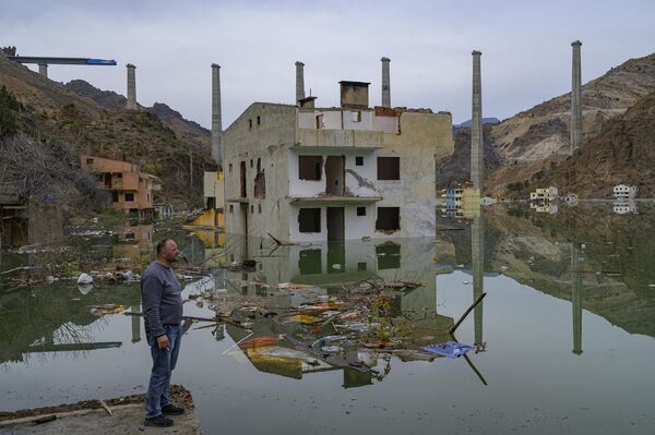 Местный житель смотрит на свой город, затопленный искусственным озером, образованным плотиной, удерживающей течение реки Корух (также называемой Чорохи) в Юсуфели, провинция Артвин, на северо-востоке Турции, 4 апреля 2023 года. - Sputnik Молдова