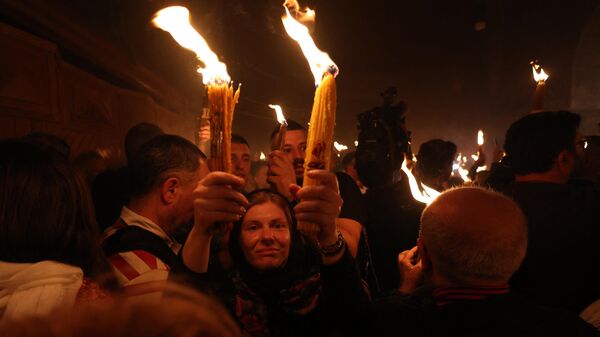 Creștinii ortodocși cu lumânări aprinse în timpul ceremoniei Focului Sfânt de la Biserica Sfântul Mormânt din Orașul Vechi al Ierusalimului - Sputnik Moldova