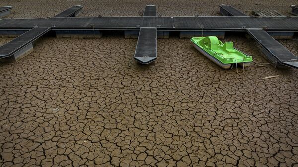 Зеленый катамаран на треснувшей земле в результате засухи в порту водохранилища Сау в Испании  - Sputnik Молдова