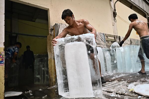 Рабочие перемещают блоки льда в хранилище на рынке свежих продуктов во время сильной жары в Бангкоке, Таиланд. - Sputnik Молдова