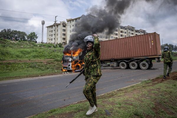 Женщина-омоновец призывает к подкреплению после того, как протестующие оппозиции подожгли грузовик, не сумев открыть контейнер, который он перевозил, во время столкновений в трущобах Кибера столицы Найроби, Кения, вторник, 2 мая 2023 года. - Sputnik Молдова