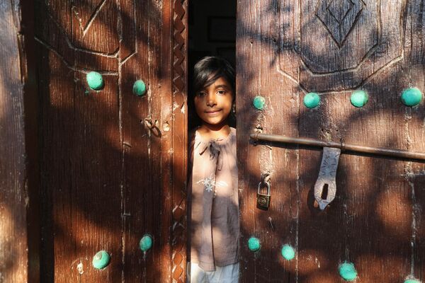 На снимке, сделанном 29 апреля 2023 года, изображена девушка, выглядывающая из дверного проема на острове Кешм в иранском заливе. - Sputnik Молдова