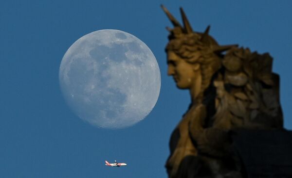 Самолет пролетает мимо статуи Лувра во время восхода растущей луны в Париже, 3 мая 2023 года. - Sputnik Молдова