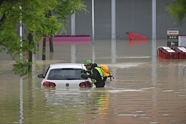 Спасатель ищет в машине пропавших без вести возле супермаркета в затопленной зоне в Чезене, Италия. - Sputnik Молдова