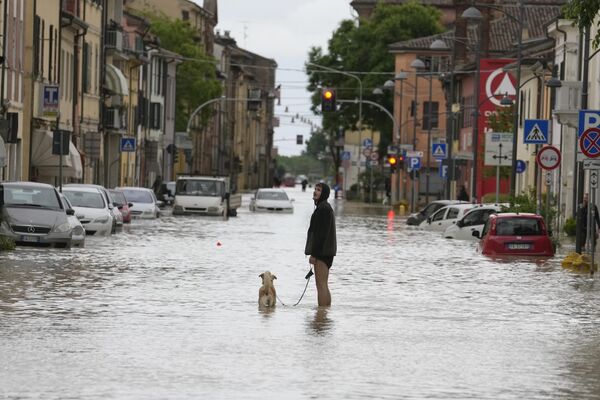 Мужчина выгуливает свою собаку по затопленной улице в Кастель-Болоньезе, Италия. - Sputnik Молдова