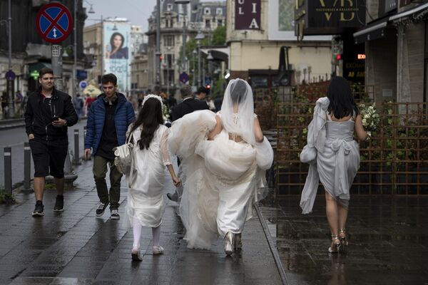 Невеста несет свое платье, прогуливаясь после дождя по центру Бухареста, Румыния, суббота, 27 мая 2023 года. - Sputnik Молдова