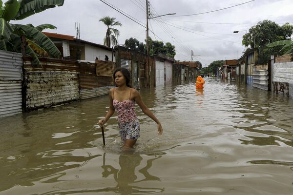 Женщина идет по затопленной улице, в то время как сотрудники гражданской защиты ищут людей для эвакуации после проливных дождей, вызванных тропическими волнами, которые затронули несколько населенных пунктов в городе Валенсия, штат Карабобо, Венесуэла, 30 мая 2023 года. - Sputnik Молдова