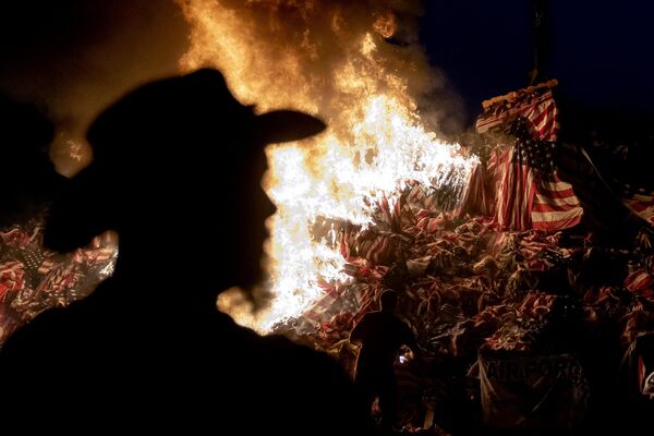 Человек наблюдает, как добровольцы зажигают сторожевой огонь в День памяти в Сиракузах, штат Нью-Йорк, 28 мая 2023 года. - Sputnik Молдова