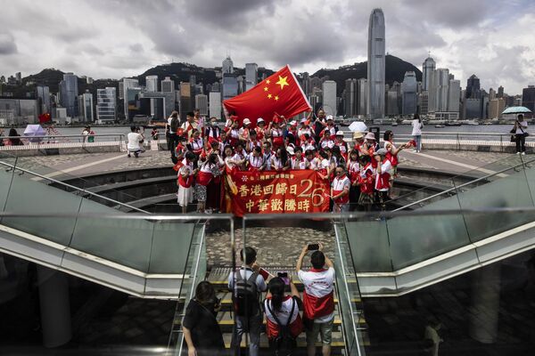Oamenii flutură steaguri ale Hong Kongului și Chinei pe malul acvatic Tsim Sha Tsui din Hong Kong la 1 iulie 2023, în timp ce sărbătoresc cea de-a 26-a aniversare de la predarea orașului de Marea Britanie către China. (Foto de ISAAC LAWRENCE / AFP) - Sputnik Moldova