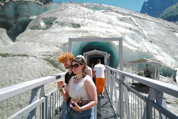 Turiști merg pe o pasarelă pentru a vizita Grotte de Glace (Peștera de Gheață) din Mer de Glace (Marea de Gheață) în Chamonix-Mont-Blanc, în Alpii francezi, la 11 iulie 2023. - Sputnik Moldova