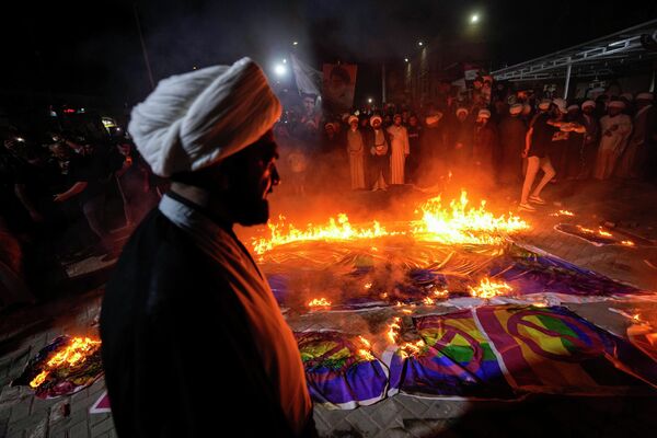 Сторонники лидера мусульман-шиитов Муктады Садра в Багдаде сжигают радужные флаги во время демонстрации в Садр-Сити в ответ на сожжение Корана в Швеции. - Sputnik Молдова