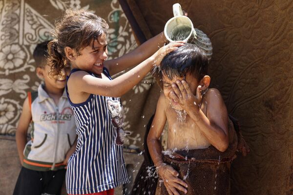 Девочка обливает мальчика водой из-за жары в городе Газа. - Sputnik Молдова