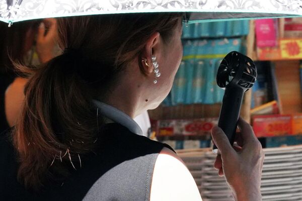 Девушка с ручным вентилятором на улице Токио. - Sputnik Молдова