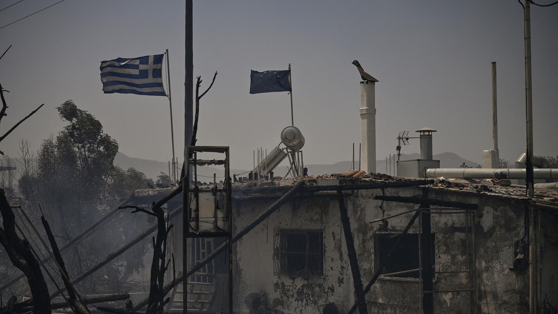 Развевающиеся греческие и европейские флаги на сгоревшем здании на греческом острове Родос - Sputnik Moldova, 1920, 24.07.2023