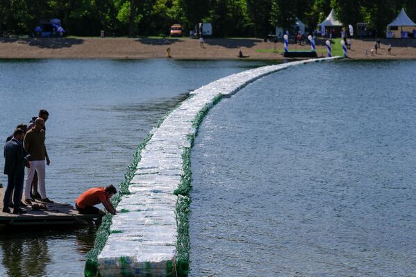 Люди осматривают плавучий мост из пластиковых бутылок, расположенный на озере Ада Циганлия в Белграде, что станет попыткой побить рекорд Гиннесса. Сербия, четверг, 27 июля 2023 года.  - Sputnik Молдова
