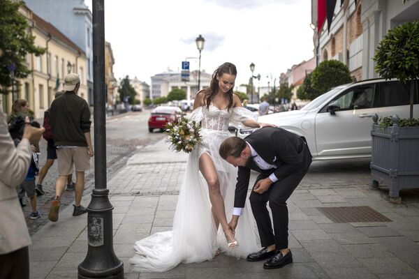 Жених помогает невесте снять обувь в Старом городе Вильнюса, Литва, суббота, 22 июля 2023 года. - Sputnik Молдова