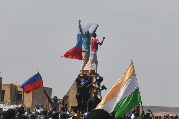 Протестующие размахивают нигерийскими и российскими флагами, собираясь во время митинга в поддержку нигерийской хунты в Ниамее. - Sputnik Молдова