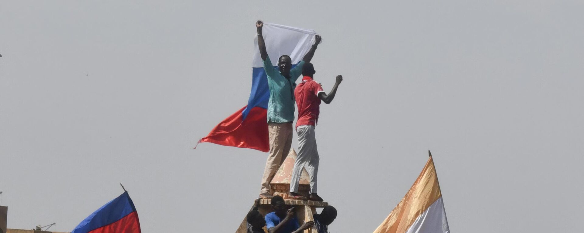 Протестующие размахивают нигерийскими и российскими флагами, собираясь во время митинга в поддержку нигерийской хунты в Ниамее - Sputnik Молдова, 1920, 19.08.2023