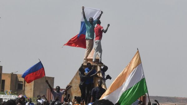 Протестующие размахивают нигерийскими и российскими флагами, собираясь во время митинга в поддержку нигерийской хунты в Ниамее - Sputnik Молдова