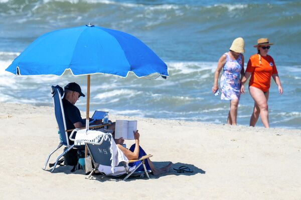 Президент США Джо Байден и первая леди Джилл Байден отдыхают под зонтиком на пляже Рехобот, США. - Sputnik Молдова