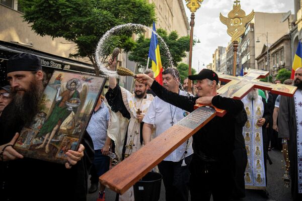 Бизнесмен Джордже Бекали вместе со священнослужителями Румынской православной церкви окропляет святой водой проспект Каля Викторией в Бухаресте, где накануне проходил &quot;прайд гордости&quot;. - Sputnik Молдова