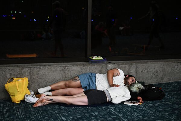 Пассажиры пытаются спать на полу терминала аэропорта в ожидании задержанных и отмененных рейсов после лесных пожаров на западе Мауи в Кахулуи, Гавайи. - Sputnik Молдова