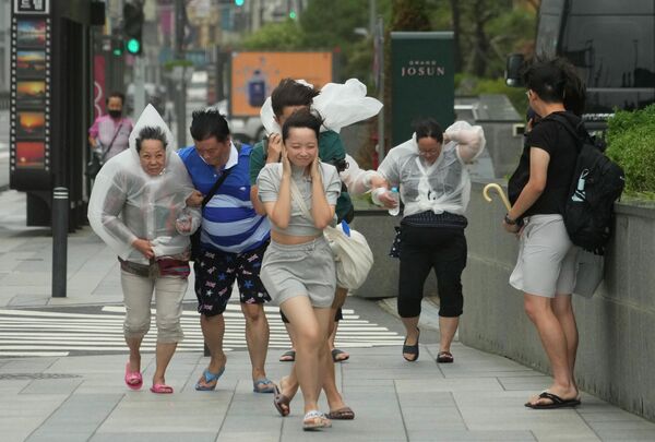 Люди борются с дождем и ветром во время тропического шторма Ханун в Пусане, Южная Корея. - Sputnik Молдова