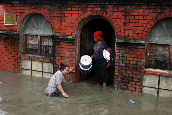 Женщина идет по затопленной улице в Катманду, Непал. - Sputnik Молдова