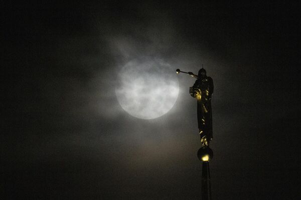 Superlună, lună albastră, se ridică printre stratul gros de nori în spatele statuiei Îngerului Moroni aflat în vârful Bisericii lui Isus Hristos a Sfinților din Zilele din Urmă din în Kensington, 30 august 2023. - Sputnik Moldova