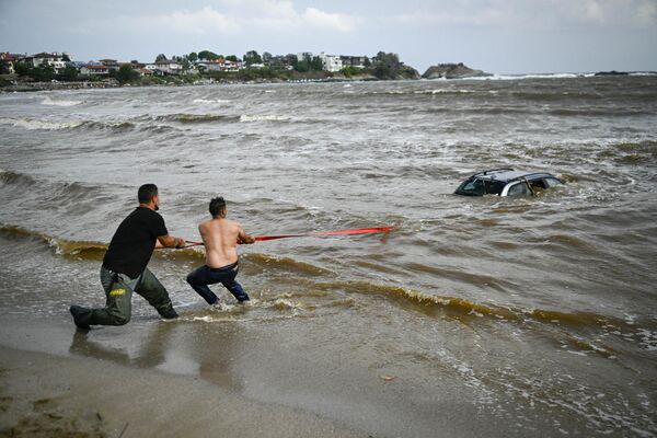 Люди пытаются вытащить автомобиль, затонувший в море в результате наводнения в Болгарии. - Sputnik Молдова
