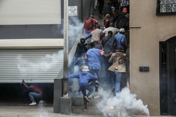 Сторонники оппозиции бегут в укрытие, когда сотрудники полиции по борьбе с беспорядками используют слезоточивый газ для их разгона в Антананариву, Мадагаскар. - Sputnik Молдова