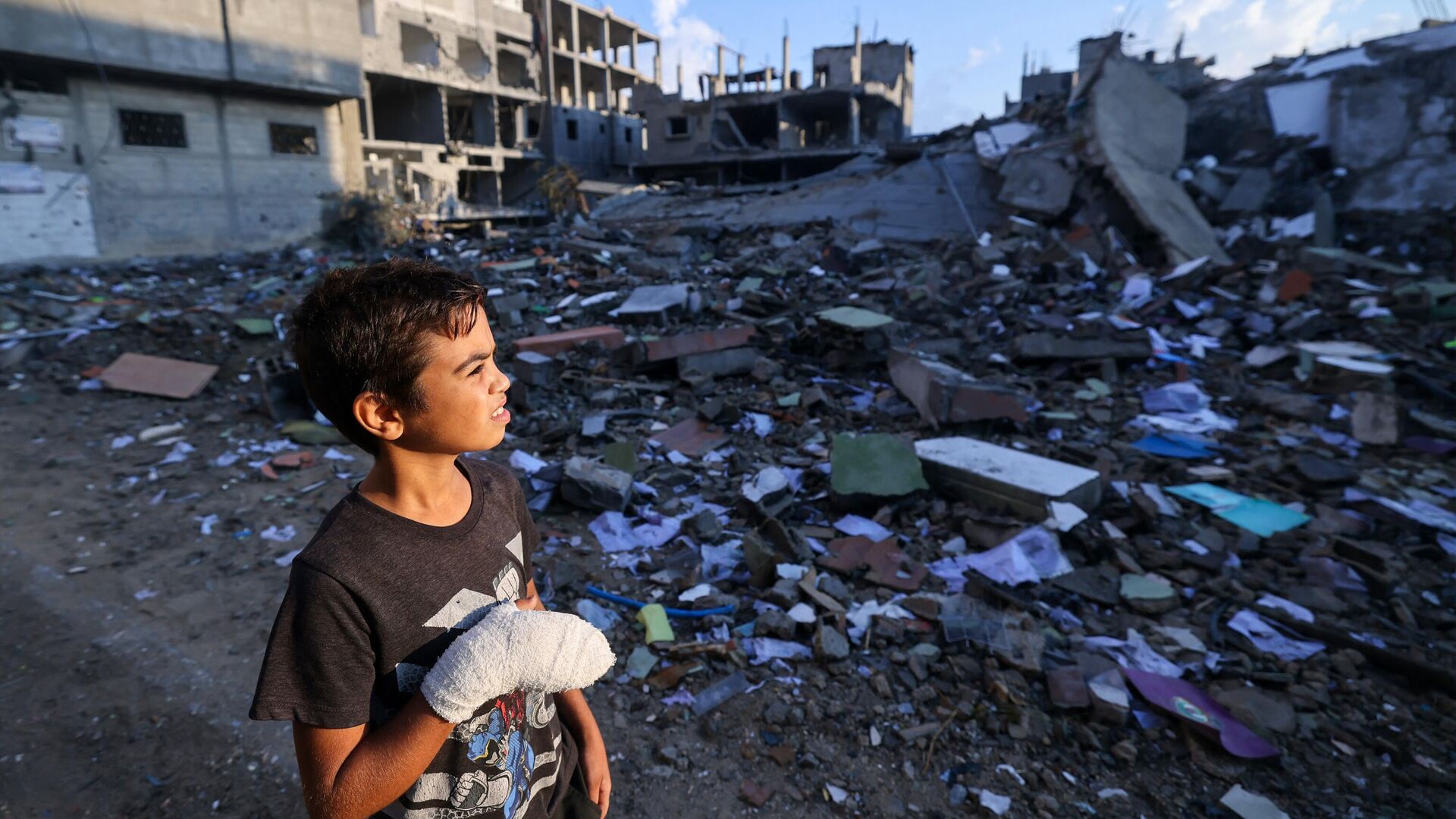 Раненый палестинский мальчик смотрит на здания, разрушенные во время израильских авиаударов, недалеко от его дома в лагере беженцев Рафах на юге сектора Газа - Sputnik Moldova, 1920, 30.10.2023