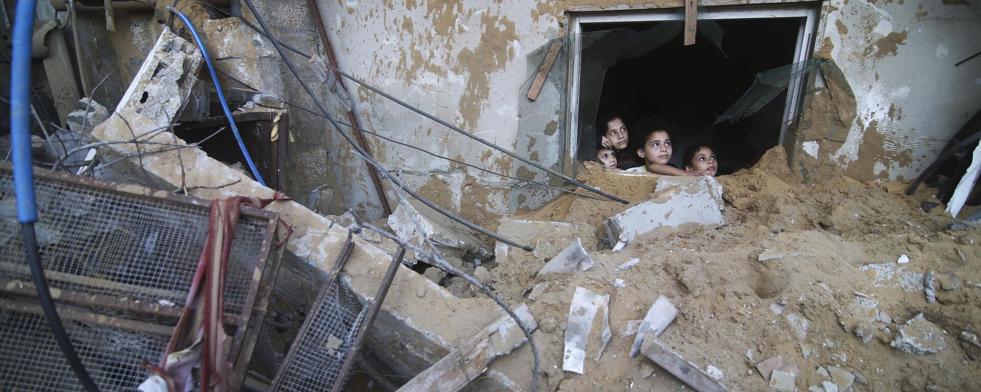 Палестинские дети выглядывают из-под руин разрушенного здания в результате израильских авиаударов в Рафахе, сектор Газа - Sputnik Moldova, 1920, 25.12.2023