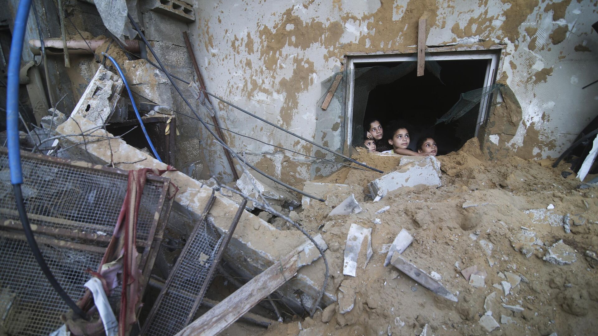 Палестинские дети выглядывают из-под руин разрушенного здания в результате израильских авиаударов в Рафахе, сектор Газа - Sputnik Moldova, 1920, 25.12.2023