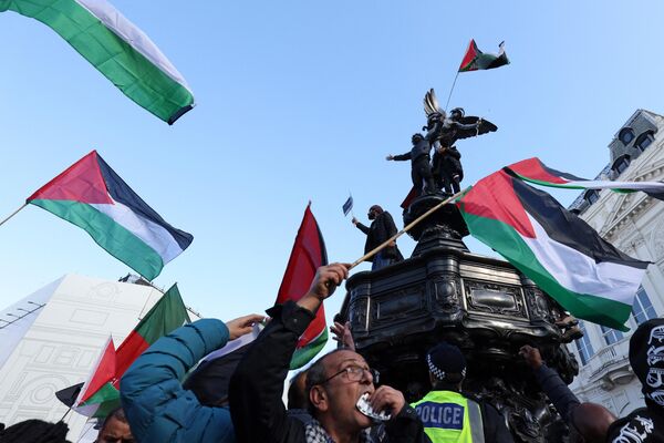 Протестующие с палестинскими флагами поднимаются на статую Эроса на площади Пикадилли во время &quot;Марша за Палестину&quot;, части пропалестинской национальной демонстрации, в Лондоне 14 октября 2023 года. - Sputnik Молдова