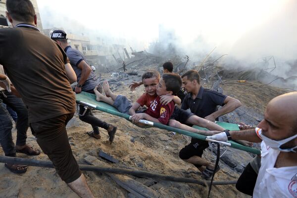Палестинцы эвакуируют двух раненых мальчиков из-под разрушений после авиаударов Израиля по городу Газа, среда, 25 октября 2023 года. - Sputnik Молдова