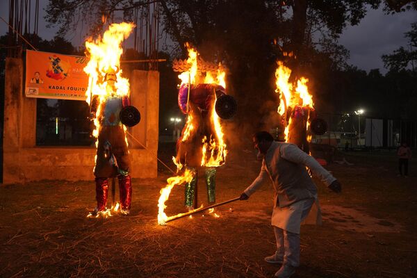 Мужчина сжигает чучела короля демонов Раваны, своего брата Кумбхакарны и сына Мегханады, отмечая окончание фестиваля Душера в Сринагаре, контролируемом Индией Кашмире, во вторник, 24 октября 2023 года - Sputnik Молдова